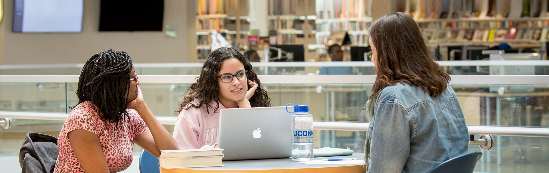 three students sitting in library talking