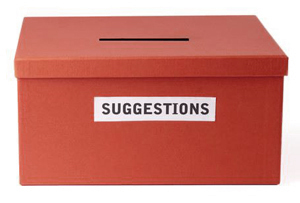Red box with a lid that has a slit in it and a label that reads SUGGESTIONS in all capital letters